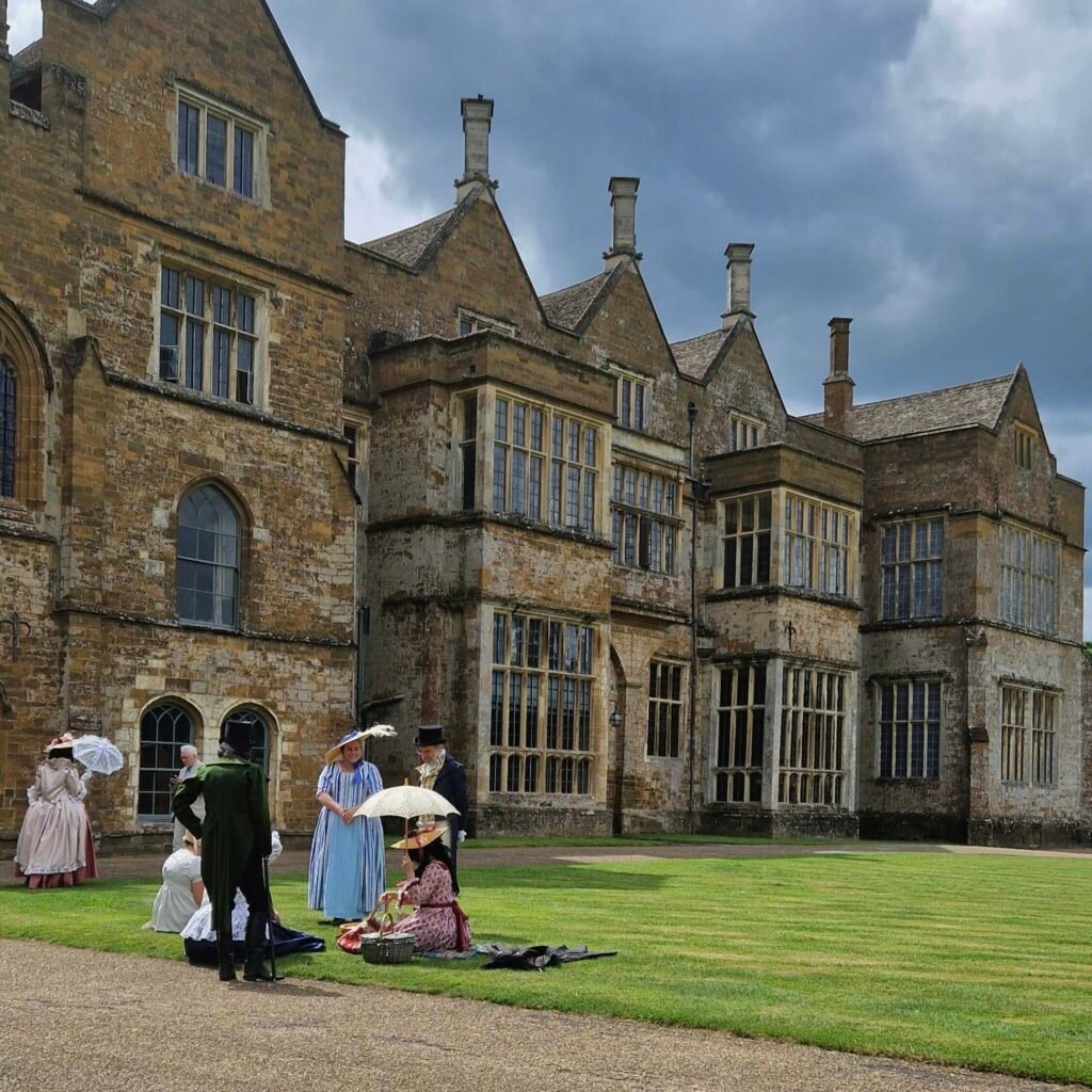 Broughton Castle and people in historic costumes in front of it