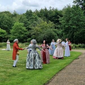 People in historic costumes dancing in front of Broughton Castle